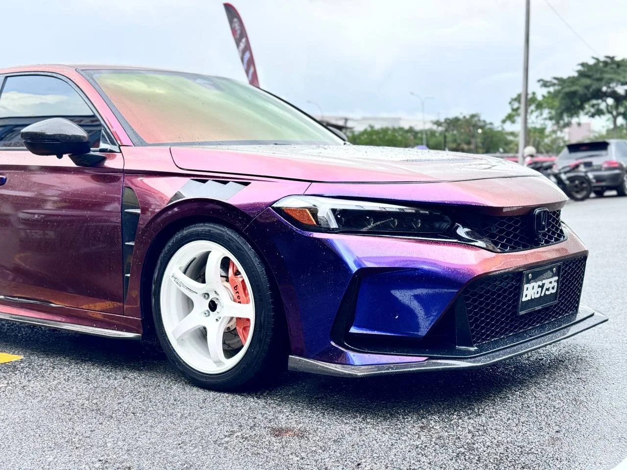 Colour-shifting Honda with a white performance wheel at a community event