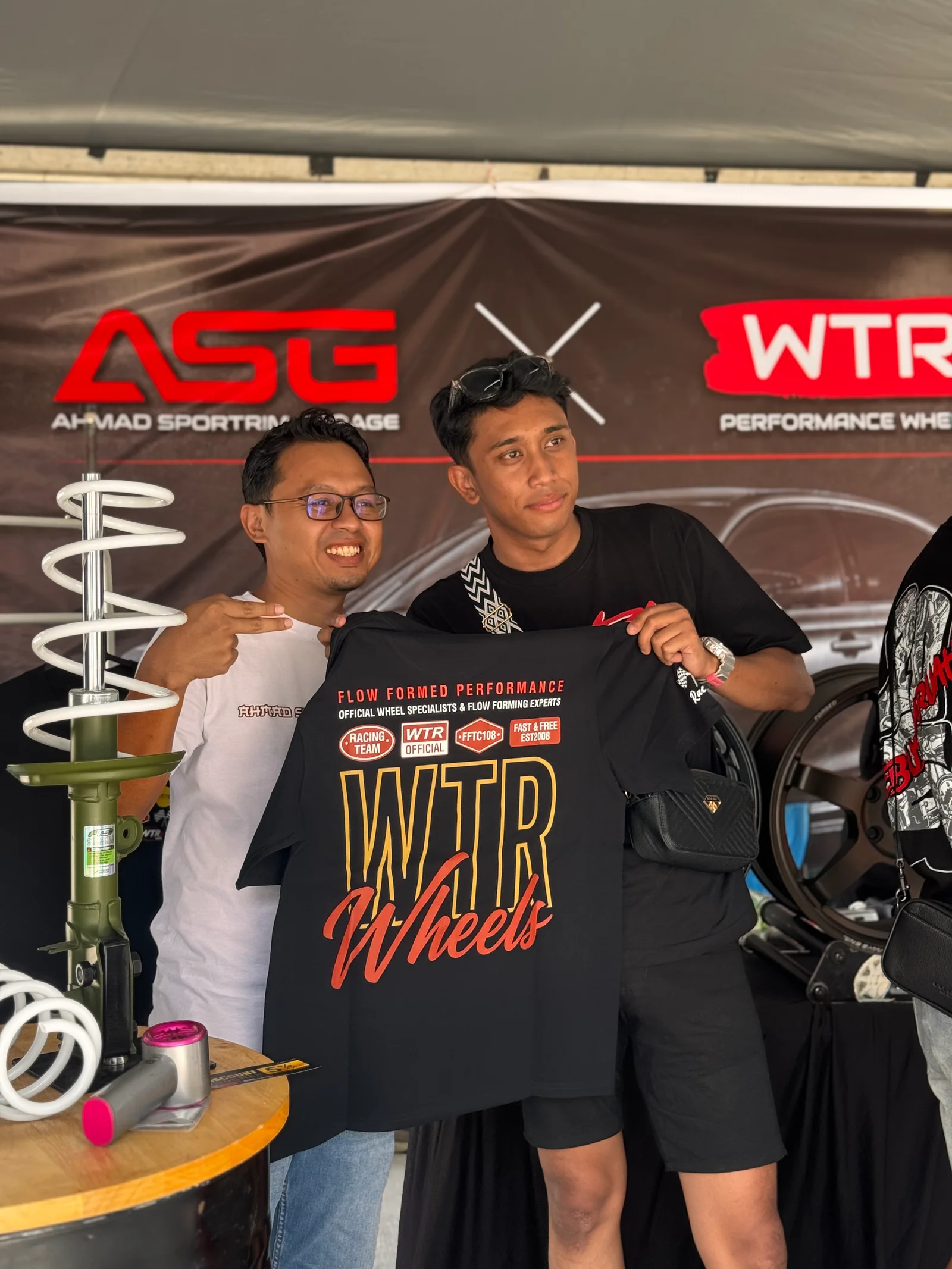 Two community members displaying WTR merchandise at the ASG event booth