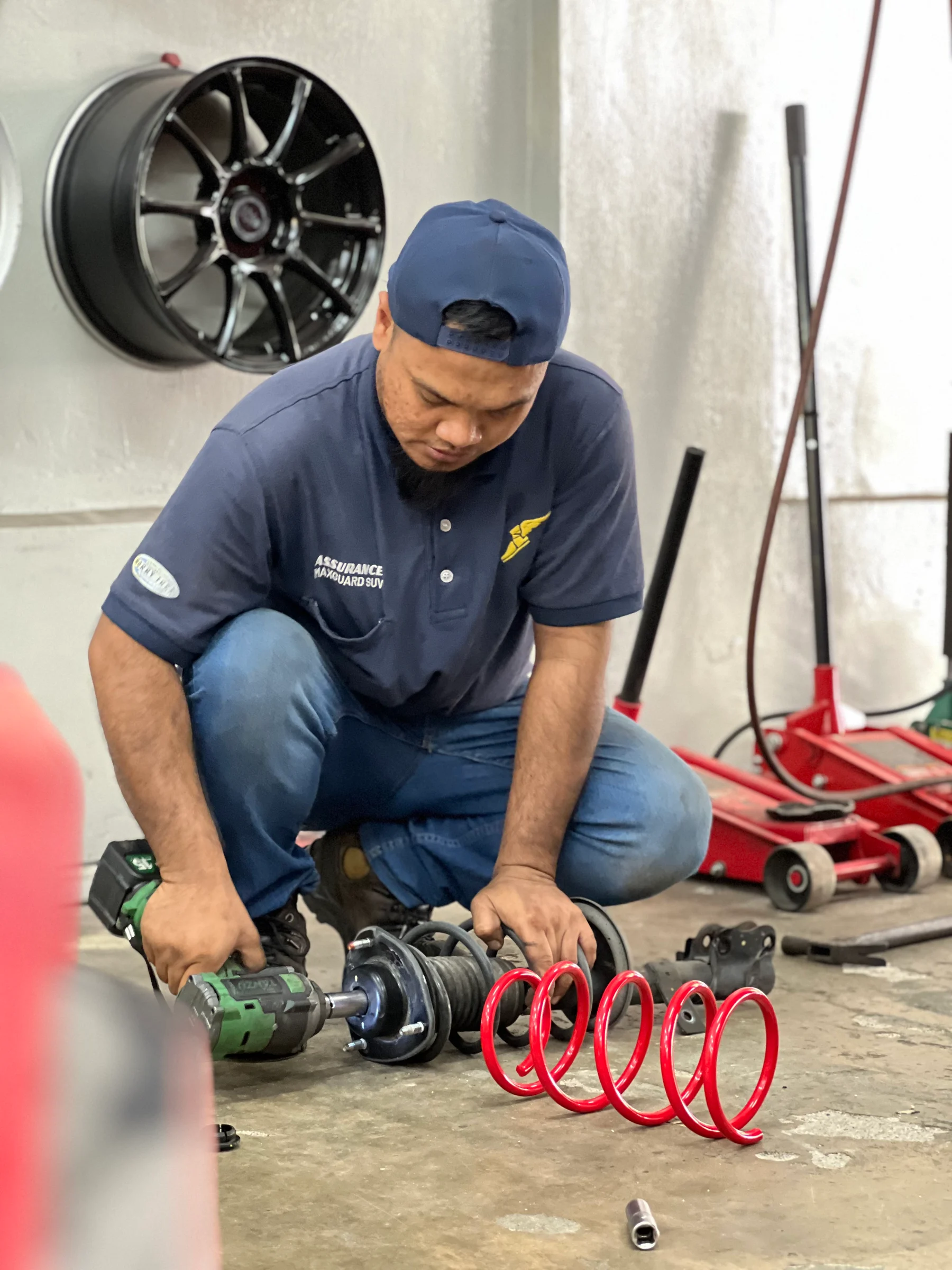ASG technician working on a suspension strut and red coil spring in the workshop